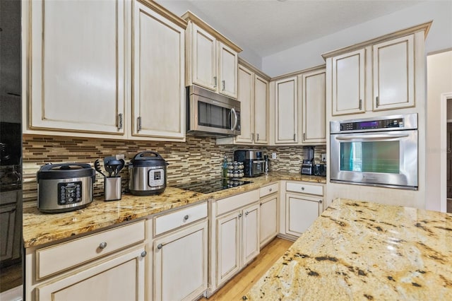 22623 Cliffside Way, Land O Lakes, FL 34639 - kitchen featuring appliances with stainless steel finishes, light wood finished floors, cream cabinets, backsplash, and light stone countertops