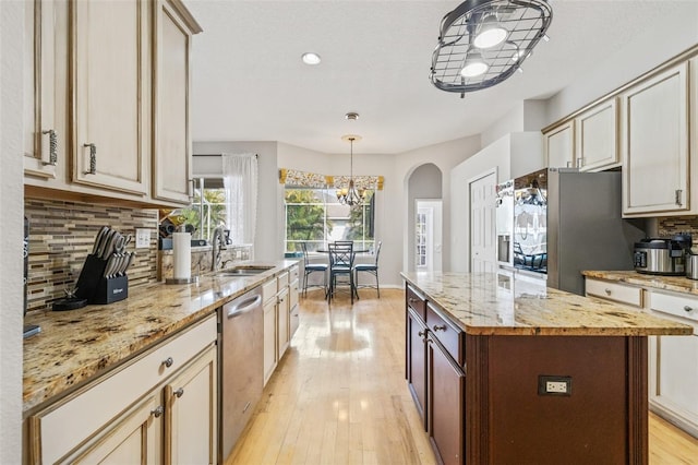 22623 Cliffside Way, Land O Lakes, FL 34639 - kitchen with appliances with stainless steel finishes, backsplash, light wood-style flooring, arched walkways, and light stone counters