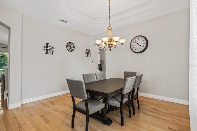 22623 Cliffside Way, Land O Lakes, FL 34639 - dining space featuring arched walkways, a raised ceiling, light wood finished floors, and a chandelier