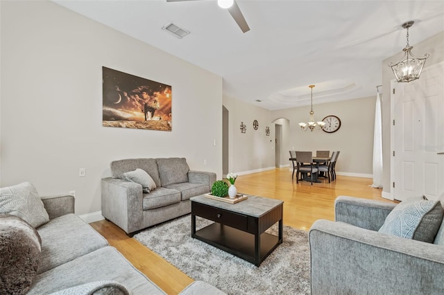 22623 Cliffside Way, Land O Lakes, FL 34639 - living area featuring arched walkways, a chandelier, light wood-type flooring, a ceiling fan, and a tray ceiling