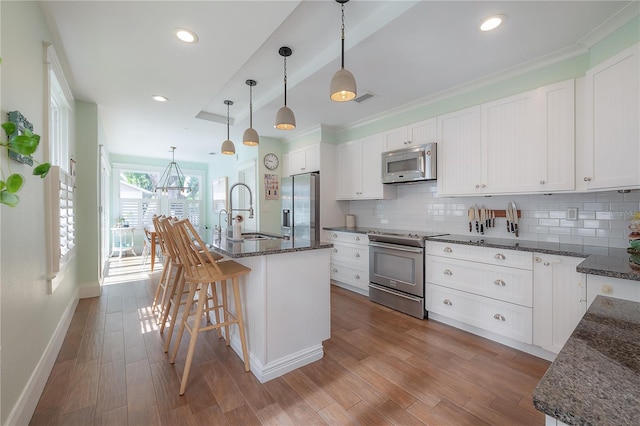 1407 S Moody Ave, Tampa, FL 33629 - kitchen featuring appliances with stainless steel finishes, decorative backsplash, a kitchen bar, white cabinetry, and recessed lighting
