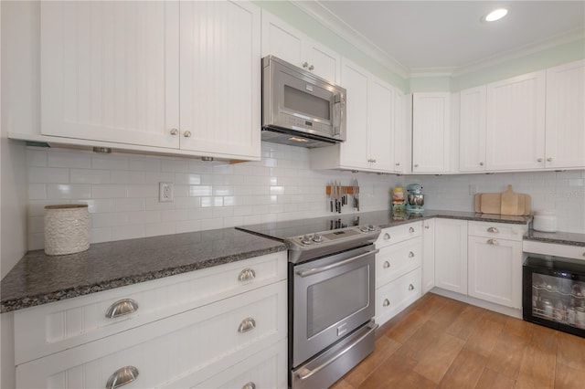 1407 S Moody Ave, Tampa, FL 33629 - kitchen featuring stainless steel appliances, beverage cooler, ornamental molding, white cabinetry, and dark stone counters