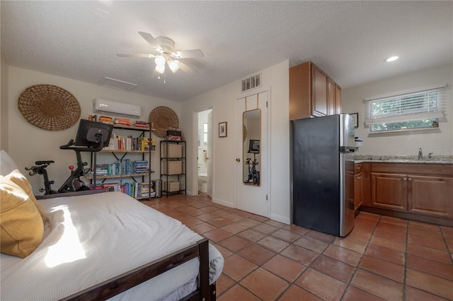 1407 S Moody Ave, Tampa, FL 33629 - bedroom featuring freestanding refrigerator, a wall mounted AC, light tile patterned floors, ensuite bathroom, and a textured ceiling