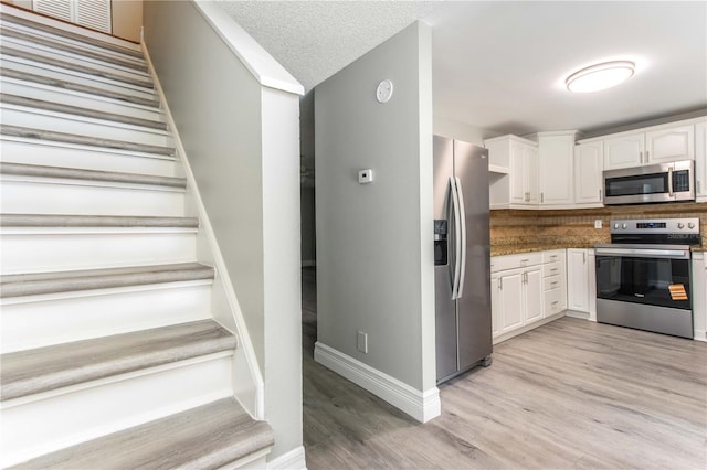 4117 Daventry Ln, Palm Harbor, FL 34685 - kitchen with appliances with stainless steel finishes, white cabinetry, light wood-style flooring, decorative backsplash, and dark countertops
