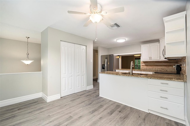 4117 Daventry Ln, Palm Harbor, FL 34685 - kitchen featuring a peninsula, light wood finished floors, dark stone counters, a ceiling fan, and white cabinetry