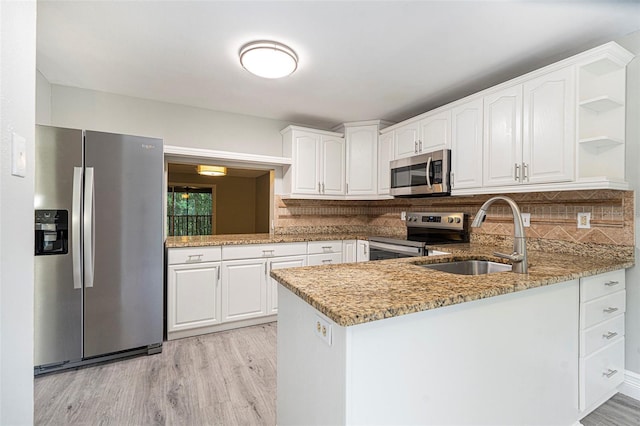 4117 Daventry Ln, Palm Harbor, FL 34685 - kitchen with appliances with stainless steel finishes, light stone countertops, open shelves, a peninsula, and white cabinetry