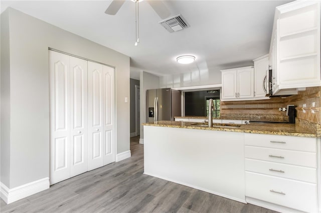 4117 Daventry Ln, Palm Harbor, FL 34685 - kitchen with a peninsula, stone counters, wood finished floors, tasteful backsplash, and white cabinetry