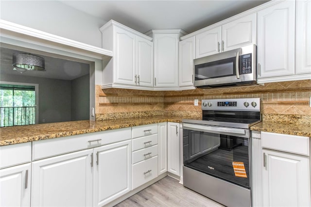 4117 Daventry Ln, Palm Harbor, FL 34685 - kitchen with appliances with stainless steel finishes, white cabinets, backsplash, and light wood-type flooring