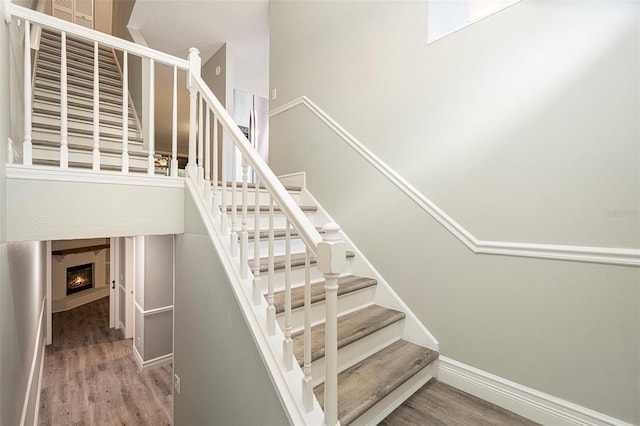 4117 Daventry Ln, Palm Harbor, FL 34685 - stairs featuring wood finished floors and a lit fireplace