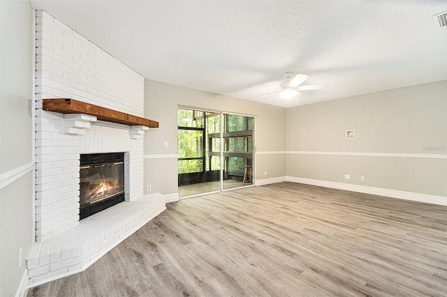 4117 Daventry Ln, Palm Harbor, FL 34685 - unfurnished living room with a textured ceiling, a brick fireplace, wood finished floors, and a ceiling fan