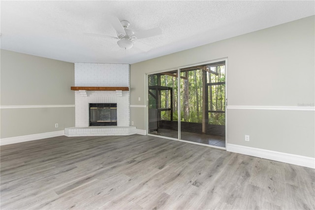 4117 Daventry Ln, Palm Harbor, FL 34685 - unfurnished living room featuring a ceiling fan, wood finished floors, a textured ceiling, and a brick fireplace