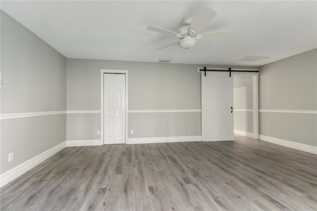 4117 Daventry Ln, Palm Harbor, FL 34685 - empty room with ceiling fan, wood finished floors, a barn door, and a textured ceiling