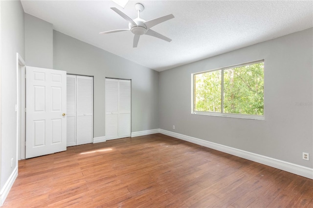 4117 Daventry Ln, Palm Harbor, FL 34685 - unfurnished bedroom with multiple closets, light wood-style floors, lofted ceiling, and ceiling fan