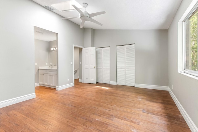 4117 Daventry Ln, Palm Harbor, FL 34685 - unfurnished bedroom featuring two closets, vaulted ceiling, light wood-type flooring, connected bathroom, and ceiling fan
