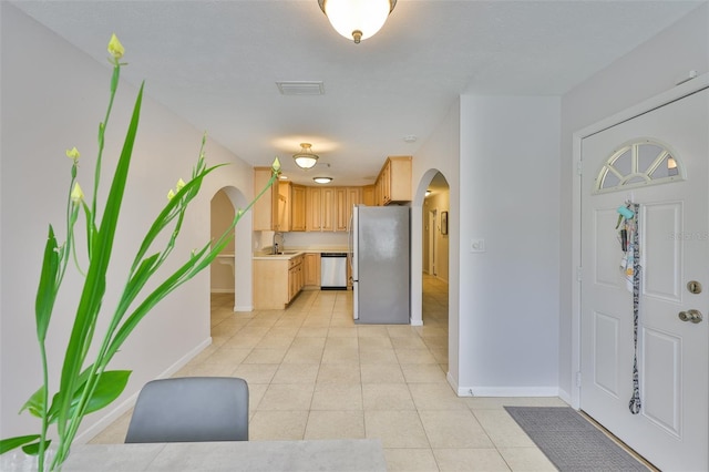 1708 Pond Lake Dr, Tampa, FL 33612 - kitchen featuring stainless steel appliances, arched walkways, light countertops, light tile patterned flooring, and light brown cabinetry