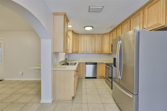 1708 Pond Lake Dr, Tampa, FL 33612 - kitchen featuring appliances with stainless steel finishes, light tile patterned flooring, light countertops, arched walkways, and light brown cabinets