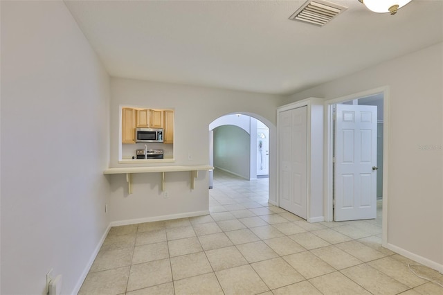 1708 Pond Lake Dr, Tampa, FL 33612 - kitchen with stainless steel microwave, arched walkways, electric stove, light countertops, and light tile patterned floors