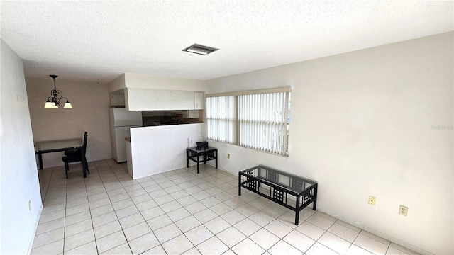 4359 Tahitian Gardens Cir Unit A, Holiday, FL 34691 - kitchen featuring freestanding refrigerator, a chandelier, a textured ceiling, white cabinets, and light tile patterned floors