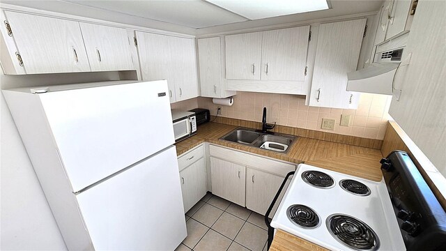 4359 Tahitian Gardens Cir Unit A, Holiday, FL 34691 - kitchen with white appliances, tasteful backsplash, and light tile patterned floors