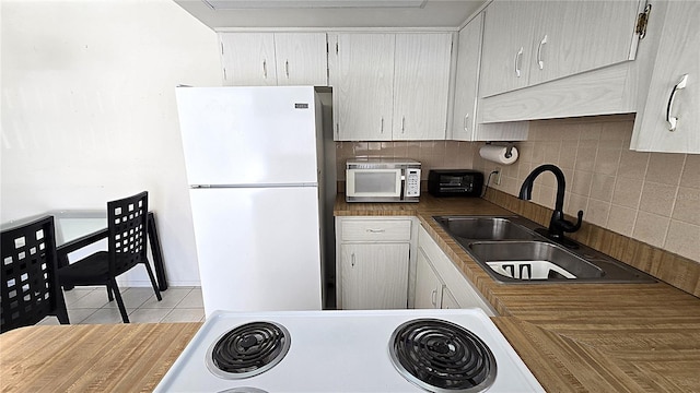 4359 Tahitian Gardens Cir Unit A, Holiday, FL 34691 - kitchen featuring white appliances, decorative backsplash, light tile patterned floors, and white cabinetry