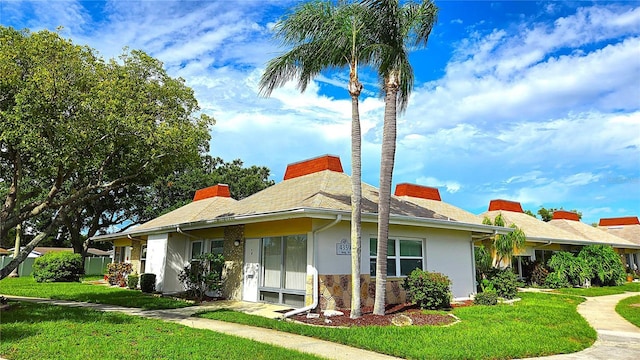 4359 Tahitian Gardens Cir Unit A, Holiday, FL 34691 - view of home's exterior with a yard, stucco siding, a chimney, and stone siding