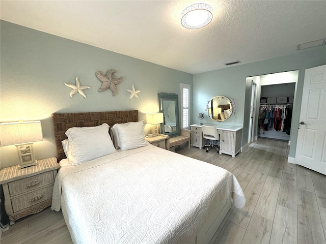 713 Rustic Oaks Dr, Palm Harbor, FL 34684 - bedroom featuring wood finished floors, a walk in closet, a closet, and a textured ceiling