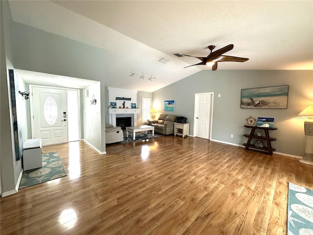 713 Rustic Oaks Dr, Palm Harbor, FL 34684 - entrance foyer featuring lofted ceiling, a ceiling fan, wood finished floors, a fireplace, and a textured ceiling