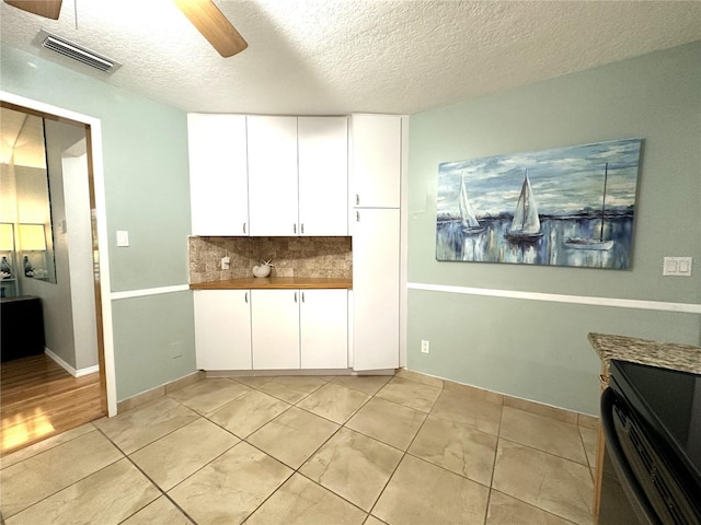 713 Rustic Oaks Dr, Palm Harbor, FL 34684 - kitchen featuring a ceiling fan, electric range, a textured ceiling, white cabinetry, and tasteful backsplash