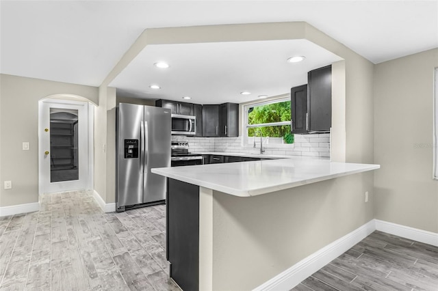 7607 New York Ave, Hudson, FL 34667 - kitchen with stainless steel appliances, light wood-type flooring, a peninsula, light countertops, and decorative backsplash