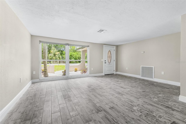 7607 New York Ave, Hudson, FL 34667 - unfurnished living room featuring wood finished floors and a textured ceiling
