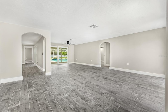 7607 New York Ave, Hudson, FL 34667 - unfurnished living room with a ceiling fan, arched walkways, and wood finished floors