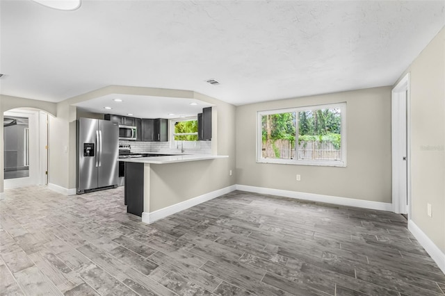 7607 New York Ave, Hudson, FL 34667 - kitchen featuring appliances with stainless steel finishes, light countertops, arched walkways, light wood finished floors, and a peninsula