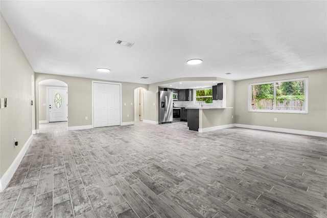 7607 New York Ave, Hudson, FL 34667 - unfurnished living room with arched walkways, wood finished floors, and recessed lighting