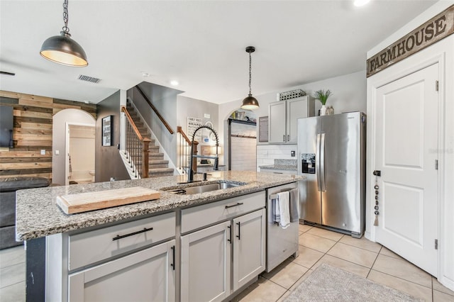 33678 Jasper Stone Dr, Wesley Chapel, FL 33543 - kitchen featuring stainless steel appliances, arched walkways, wood walls, pendant lighting, and tasteful backsplash