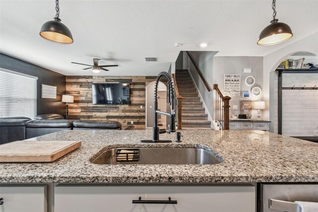 33678 Jasper Stone Dr, Wesley Chapel, FL 33543 - kitchen featuring open floor plan, wood walls, ceiling fan, light stone counters, and pendant lighting