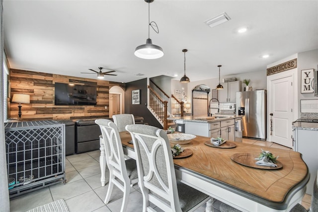33678 Jasper Stone Dr, Wesley Chapel, FL 33543 - dining area featuring wooden walls, stairs, light tile patterned floors, a ceiling fan, and arched walkways
