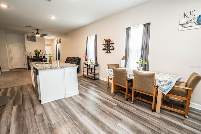 35210 Daisy Meadow Loop, Zephyrhills, FL 33541 - kitchen with light stone counters, dark wood-style flooring, ceiling fan, a center island with sink, and stainless steel dishwasher