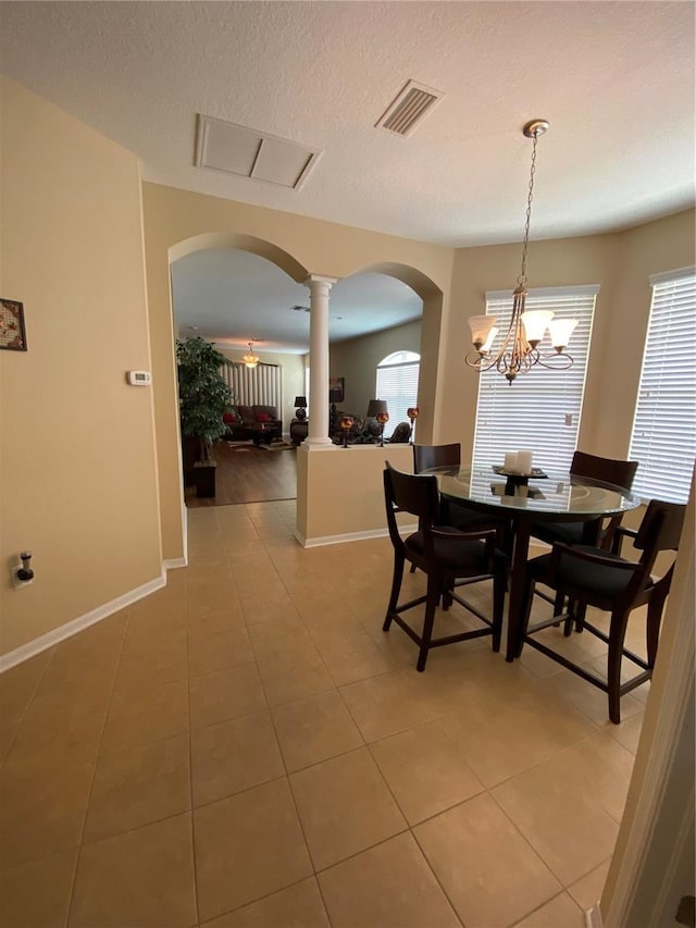 11439 Cambray Creek Loop, Riverview, FL 33579 - dining space featuring arched walkways, decorative columns, a chandelier, light tile patterned flooring, and a textured ceiling