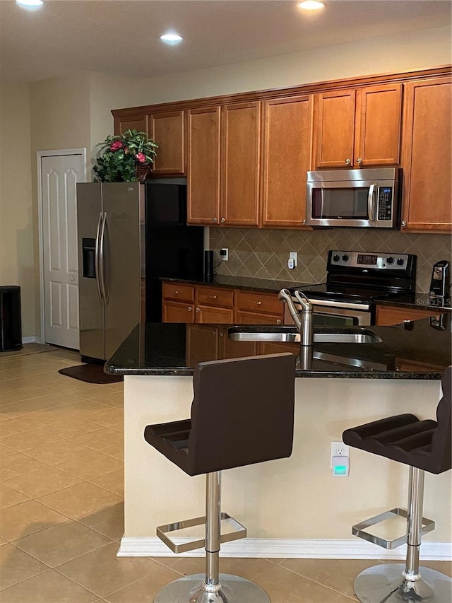 11439 Cambray Creek Loop, Riverview, FL 33579 - kitchen featuring appliances with stainless steel finishes, a kitchen breakfast bar, brown cabinetry, decorative backsplash, and recessed lighting