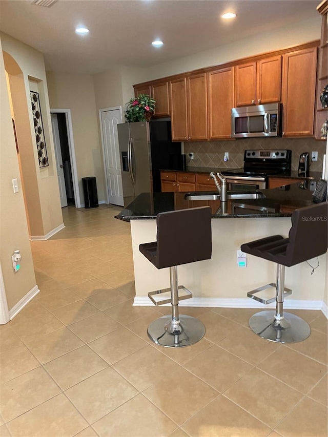 11439 Cambray Creek Loop, Riverview, FL 33579 - kitchen with stainless steel appliances, a breakfast bar, brown cabinets, tasteful backsplash, and recessed lighting