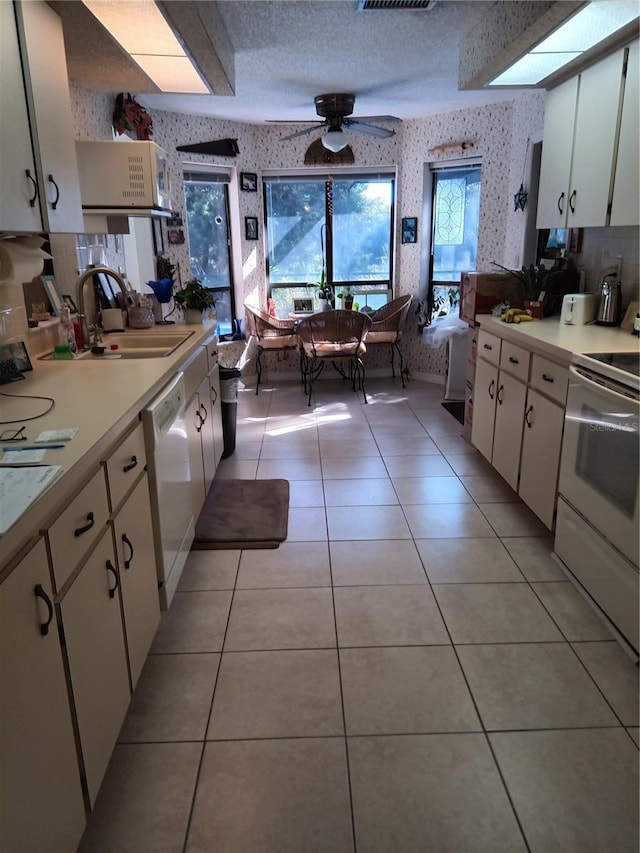 7307 Windsor Mill Rd, Hudson, FL 34667 - kitchen featuring white appliances, wallpapered walls, light countertops, white cabinetry, and ceiling fan