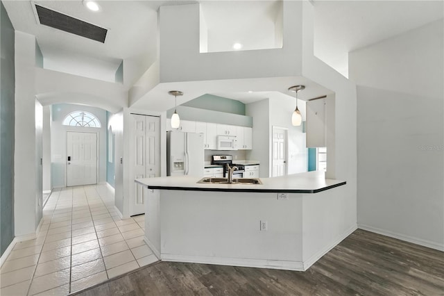 1725 Bondurant Way, Brandon, FL 33511 - kitchen with white appliances, white cabinets, a high ceiling, a peninsula, and decorative light fixtures
