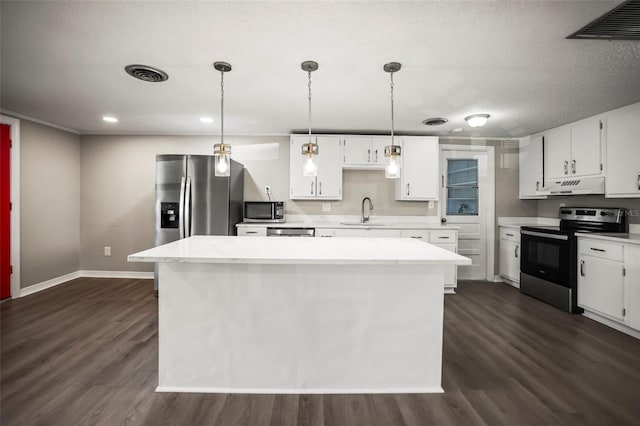 1018 Osprey Ct, Dunedin, FL 34698 - kitchen with appliances with stainless steel finishes, under cabinet range hood, white cabinets, dark wood-type flooring, and a kitchen island