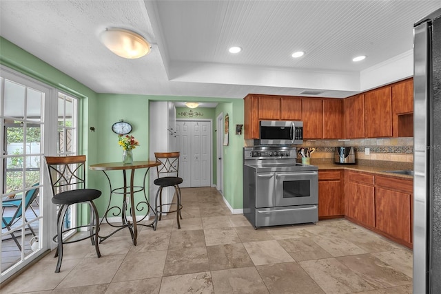 617 Valley Hill Dr, Brandon, FL 33510 - kitchen featuring stainless steel appliances, tasteful backsplash, brown cabinets, and recessed lighting