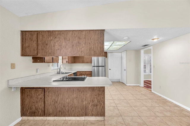 3840 Rolling Cir, Valrico, FL 33594 - kitchen with freestanding refrigerator, a peninsula, light countertops, brown cabinets, and light tile patterned floors