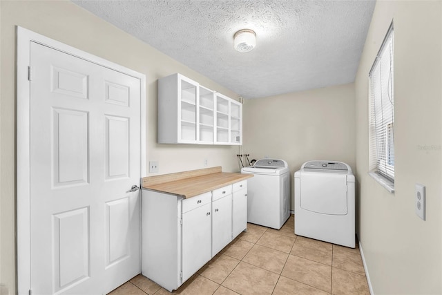 3840 Rolling Cir, Valrico, FL 33594 - laundry room featuring washing machine and dryer, a textured ceiling, cabinet space, and light tile patterned floors
