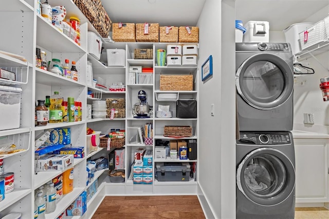 200 Main St Unit 204, Dunedin, FL 34698 - laundry area featuring stacked washer and clothes dryer, cabinet space, and wood finished floors