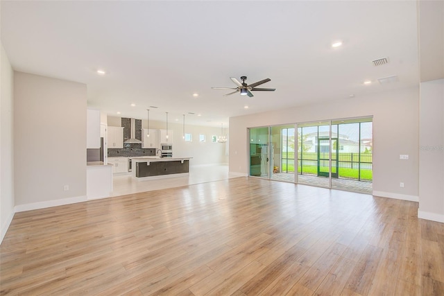 8717 Sanders Tree Loop, Wesley Chapel, FL 33545 - unfurnished living room with light wood-style flooring, a ceiling fan, and recessed lighting