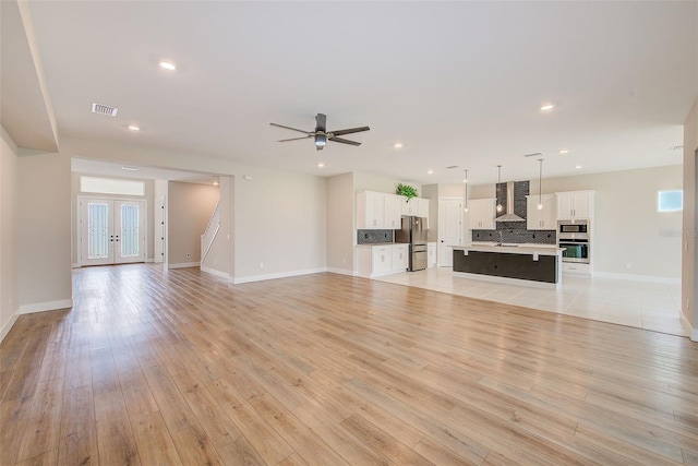 8717 Sanders Tree Loop, Wesley Chapel, FL 33545 - unfurnished living room featuring ceiling fan, recessed lighting, stairs, light wood-type flooring, and french doors