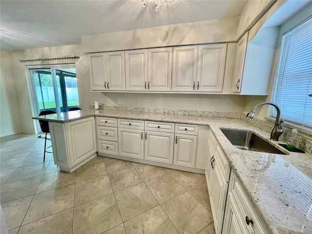7026 20th St N, Saint Petersburg, FL 33702 - kitchen with a peninsula, light tile patterned flooring, light stone countertops, and white cabinets